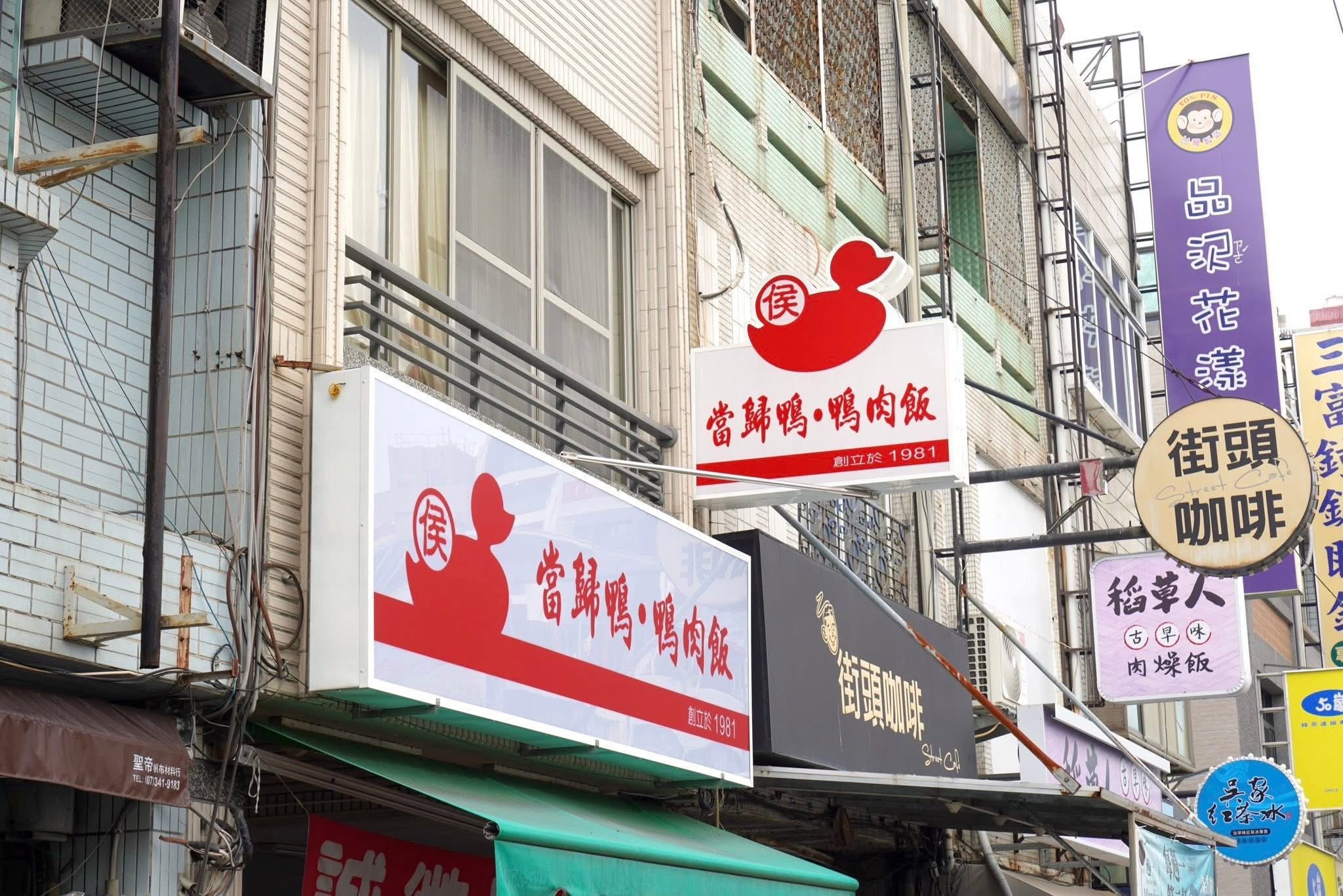 ป้ายร้านสีขาวโดดเด่นพร้อมกับรูปเป็ดและชื่อร้านเขียนด้วยลายเส้นสีแดง